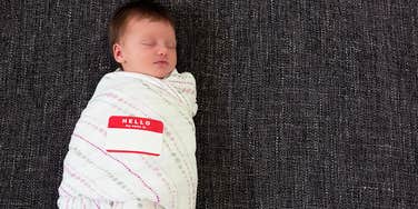 Swaddled infant wearing name sticker