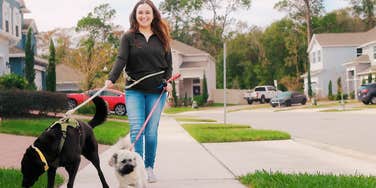 Woman taking care of her mental health, walking dog in neighborhood.