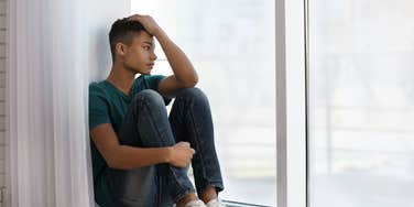 upset teenage boy looking out the window