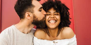 Man kissing woman on cheek, signs he wants to be with you long-term.