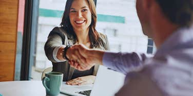 woman in office shaking hands with man 