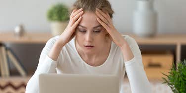 frustrated woman with hands on her forehead looking at laptop