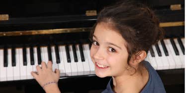 Little girl smiling while playing piano