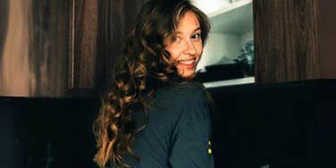 Smart, confident woman standing casually in kitchen. 