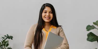 professional woman smiling while holding laptop