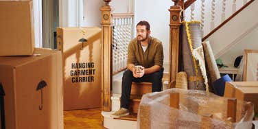 Man preparing to move out with packed boxes all around him