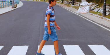 young boy walking alone on road 