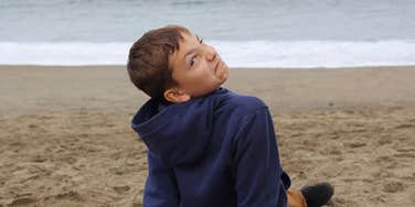 young boy making a face while sitting on the beach