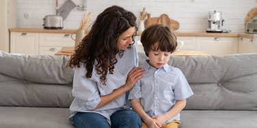 mom consoling her upset son while they sit on the couch