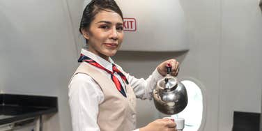 Flight attendant preparing hot cup of tea for passenger