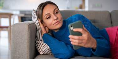 woman on couch watching tv while being on her phone