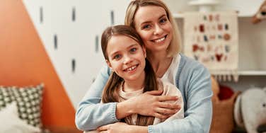 happy mother holding smiling daughter in playroom