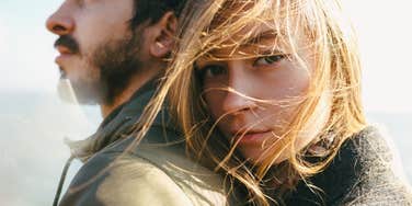 blonde haired woman rests her head on a man with a brown beard