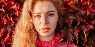 Close up shot of woman with curly blond hair and freckles looking at camera