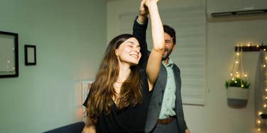 Beautiful young woman enjoying a slow dance with her husband in their living room home 