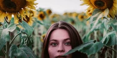 a beautiful woman appearance is hiding in a sunflower field