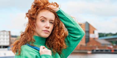 redheaded woman with curly hair posing outside