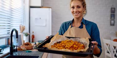 woman cooking Thanksgiving dinner in the kitchen holding up tray of food