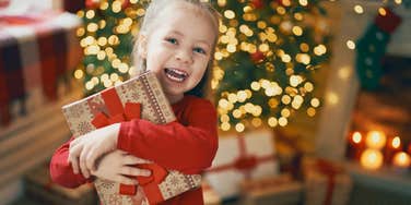 Young girl holding Christmas present from her single mom