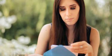 Woman looking at wedding invitation with a serious expression