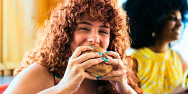 Woman eating a fast food burger that has been taken off the menu.