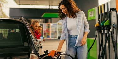 Woman with kids in the car pumping gas