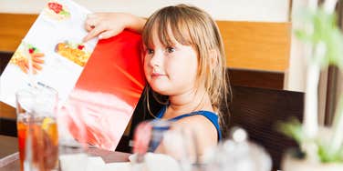 little girl pointing at what she wants on a restaurant menu