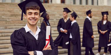 group of graduates standing outside school with one looking at camera