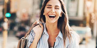 Playful woman smiling and laughing in street. 