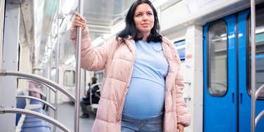 pregnant woman standing on subway