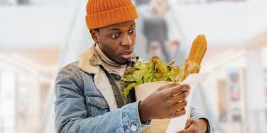 Young man looking shocked staring at his grocery store receipt. 