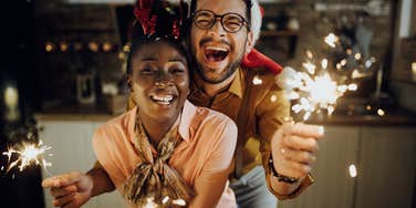 Couple smiling and holding sparklers on New Year's Eve.