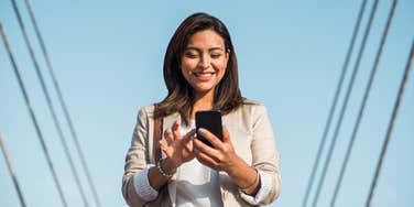 happy elegant young woman stands and uses her phone to type an important message