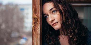 Sad woman leaning her head on a window