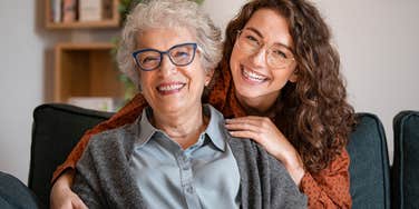 Young woman smiling and hugging her older mother on the couch