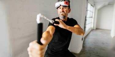 Man wearing mask, playing with nunchucks.