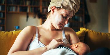 Mother wearing a hair towel, face mask and breast feeding her baby. 