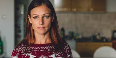 Portrait of woman standing in front of the kitchen wearing red sweater