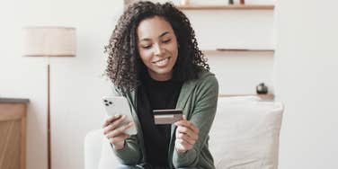 young smiling woman holding phone and credit card