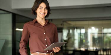 Portrait of young professional business woman standing in office.