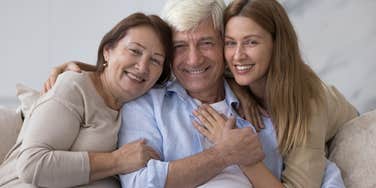 mother father and daughter smiling and embracing