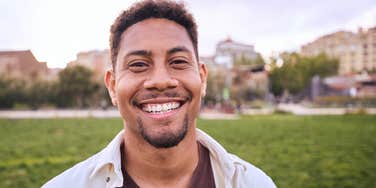 Portrait of cheerful young man standing outdoors and smiling at camera. 