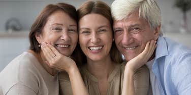 happy older parents with young adult daughter smiling