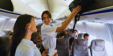 flight attendant putting bag in overhead bin