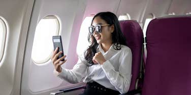 Woman taking a video of herself while flying on a plane