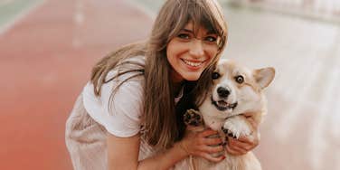 Smiling woman hugging her dog outside.