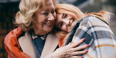 Grandmother and granddaughter hugging on the street in cold weather.