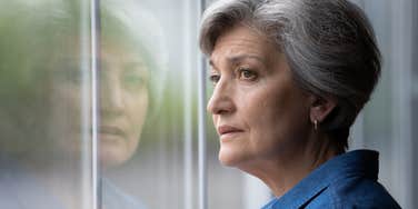 widowed grandmother looking out the window feeling sad