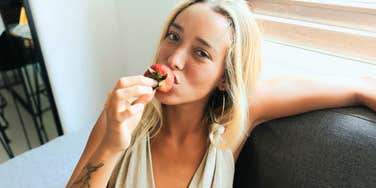 Gen-Z woman eating a strawberry.