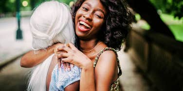 Joyful Black woman with a fun life hugging a friend 